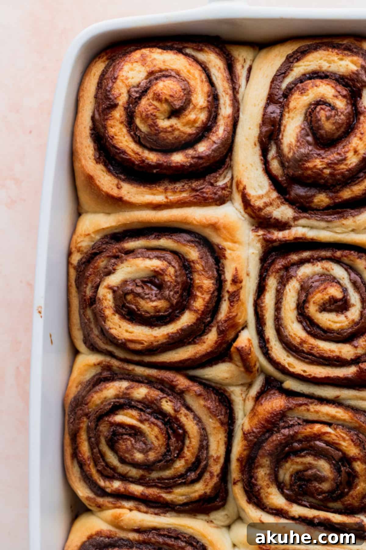 Freshly baked Nutella rolls in a pan, golden brown and ready for icing.