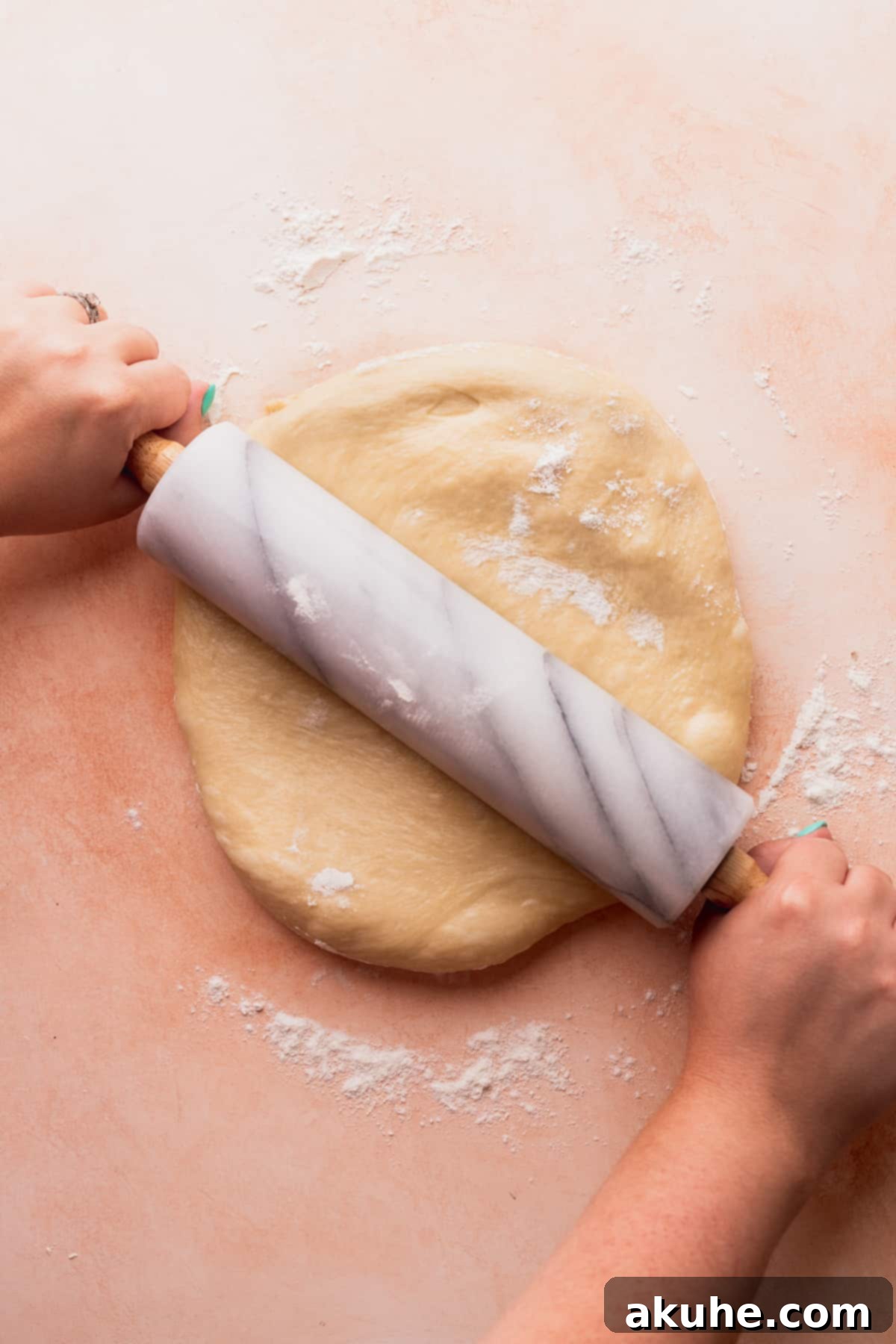 Chef rolling out the dough on a lightly floured surface.