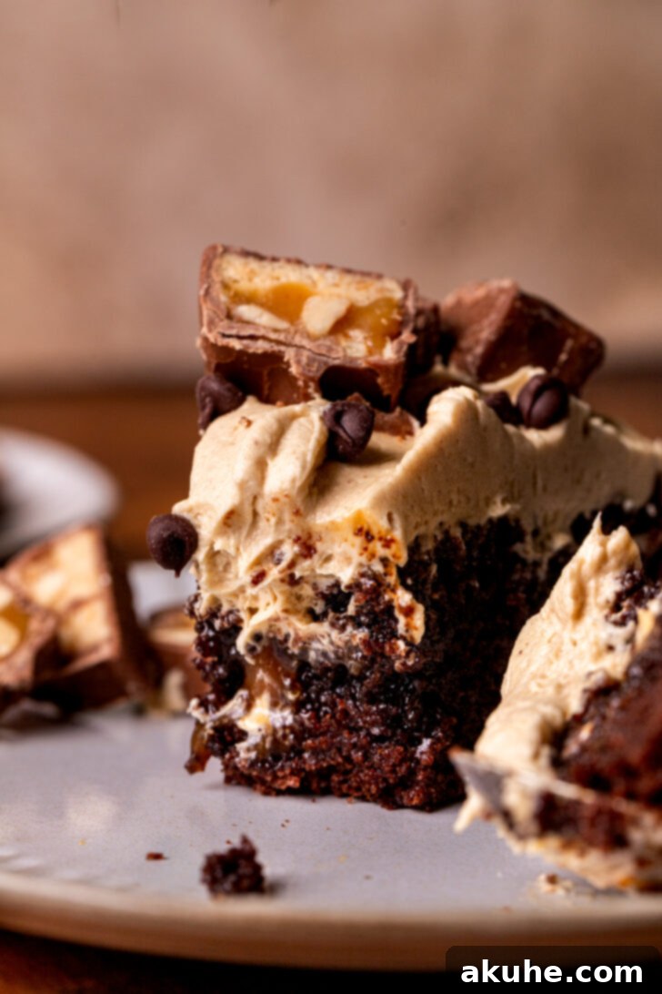 A delectable slice of Snickers cake on a plate, with a bite already taken, showcasing the moist interior and rich toppings.