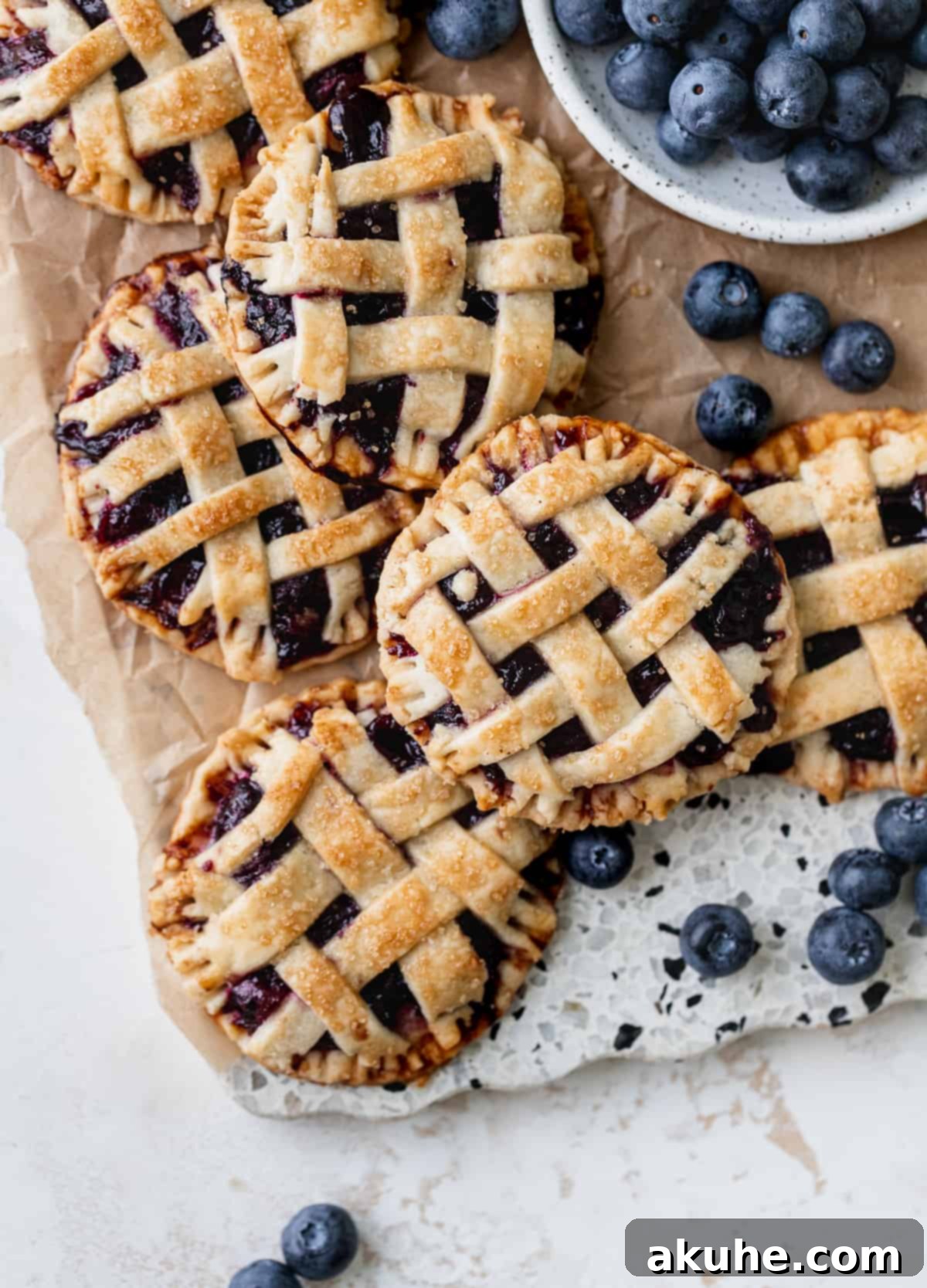 Blueberry Pie Bites 13 A charming arrangement of baked mini blueberry pies on a wooden cutting board, showcasing their golden crusts and lattice tops.