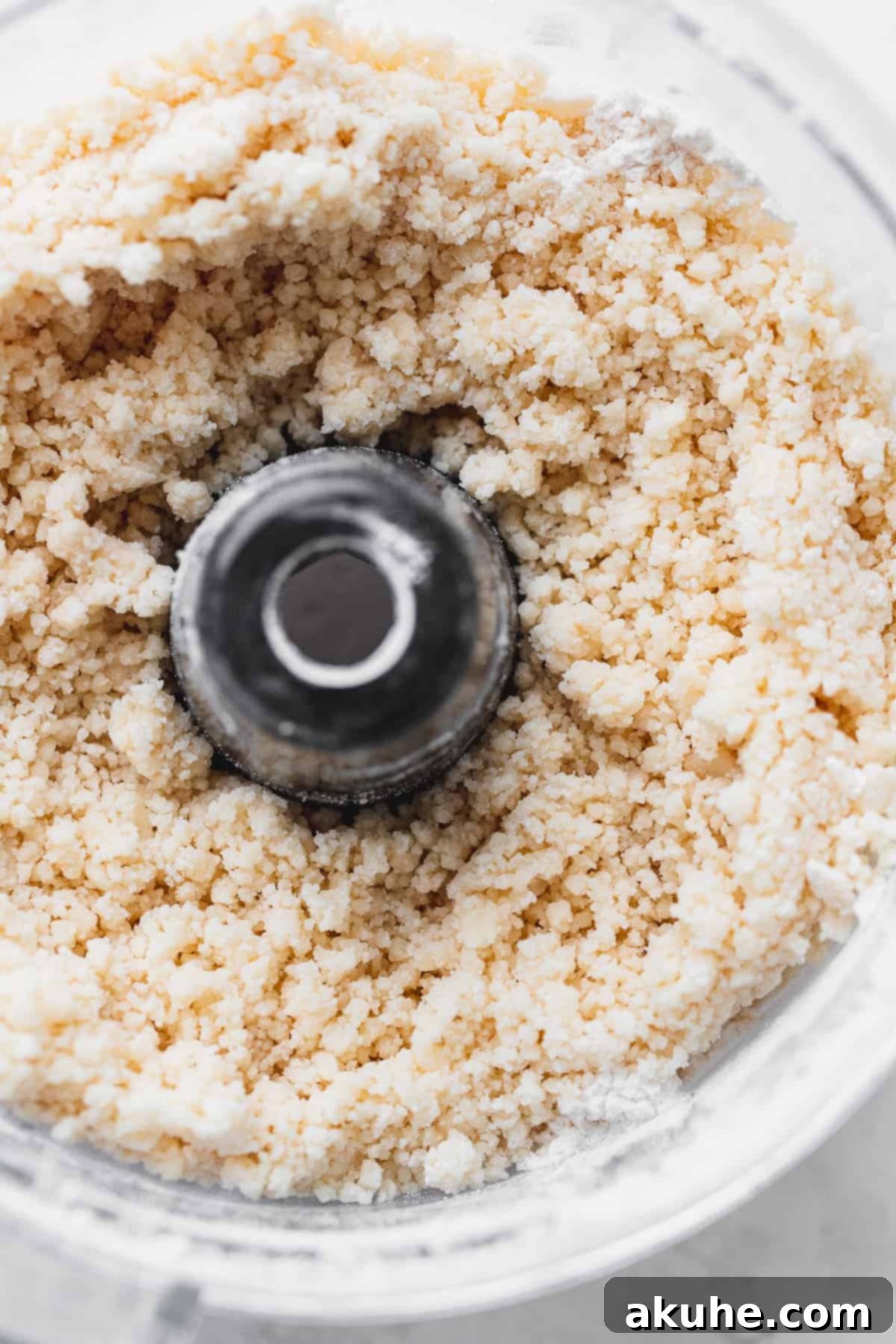 Blueberry Pie Bites 5 Step-by-step image of butter being pulsed into flour in a food processor, showing the initial crumbly texture of the pie dough.