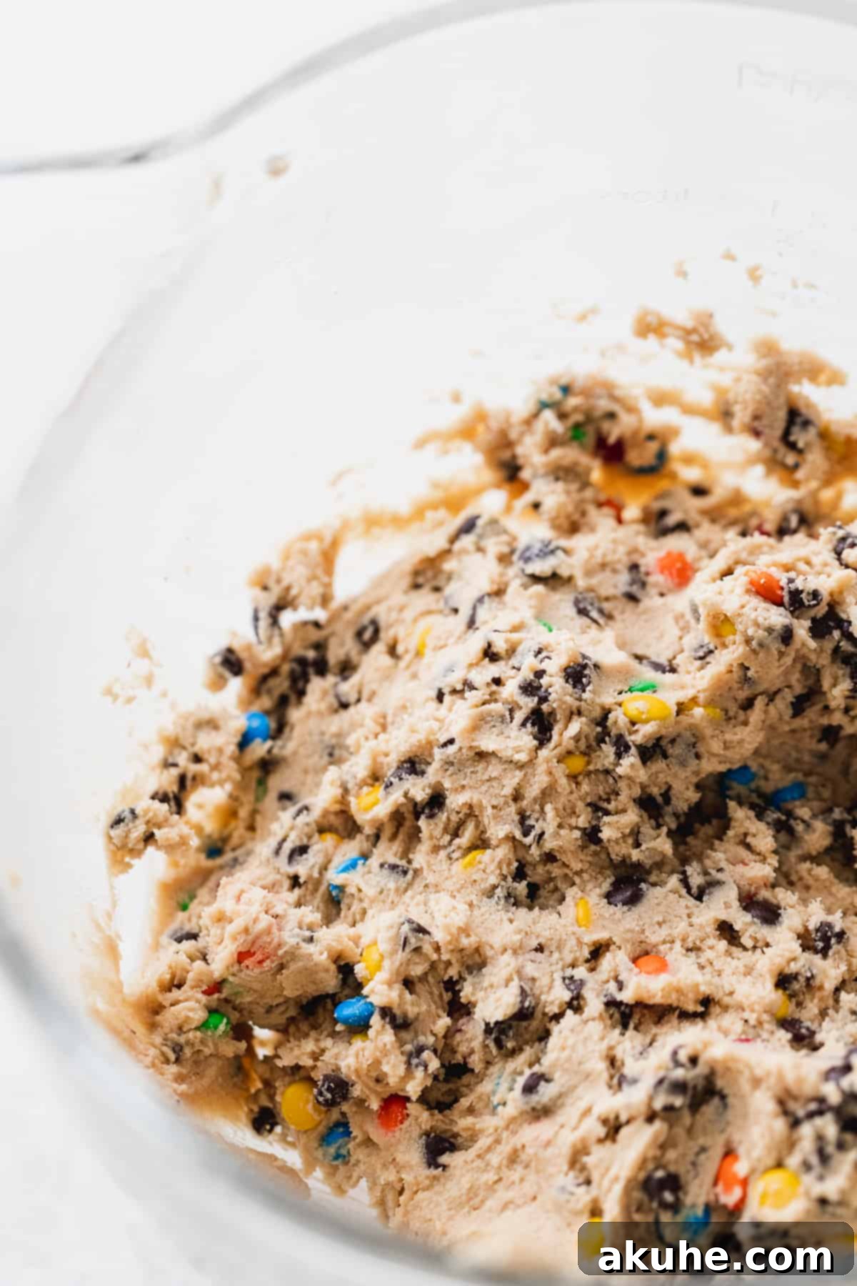Close-up of freshly mixed M&M cookie dough in a mixing bowl, showcasing the colorful candies and chocolate chips.