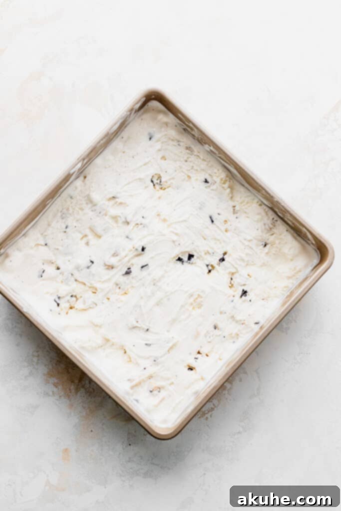 Smooth vanilla ice cream spread evenly in a metal tin, ready for freezing and cutting.