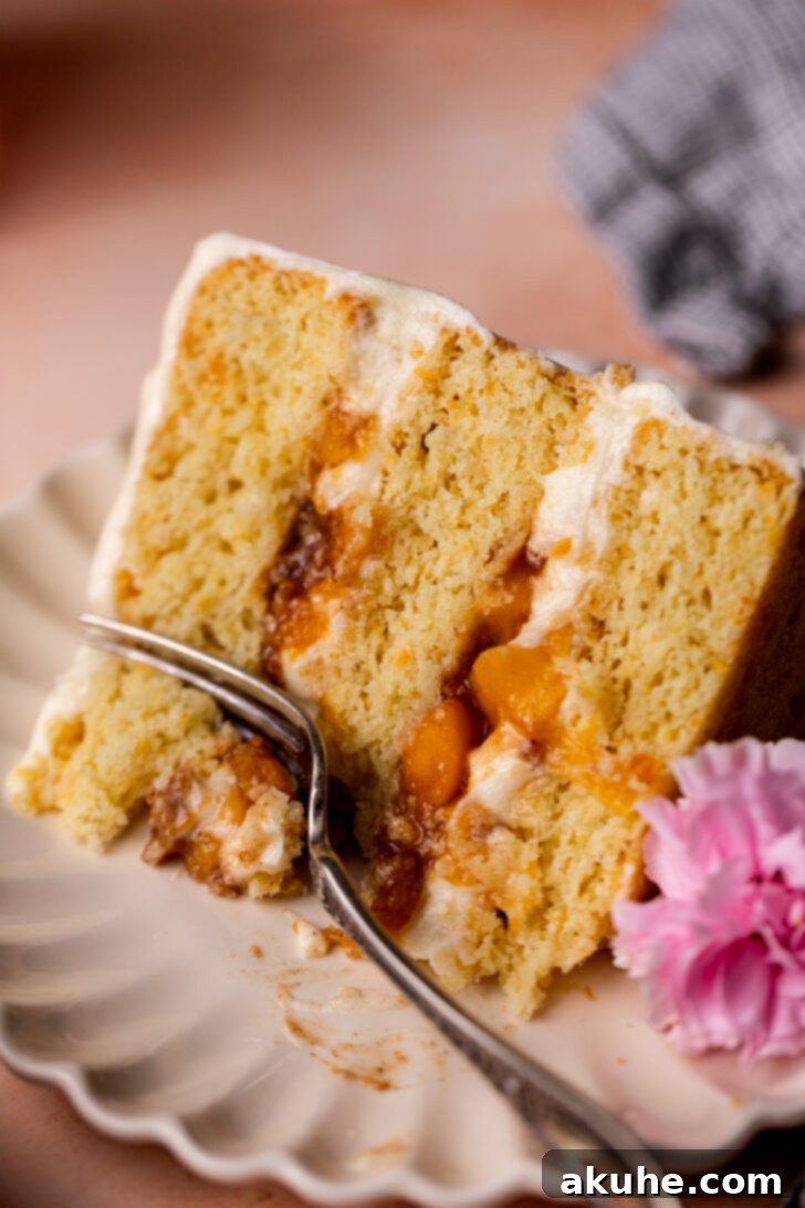 Fork inserted into a slice of Peach Cobbler Cake, showcasing its luscious layers and inviting texture.