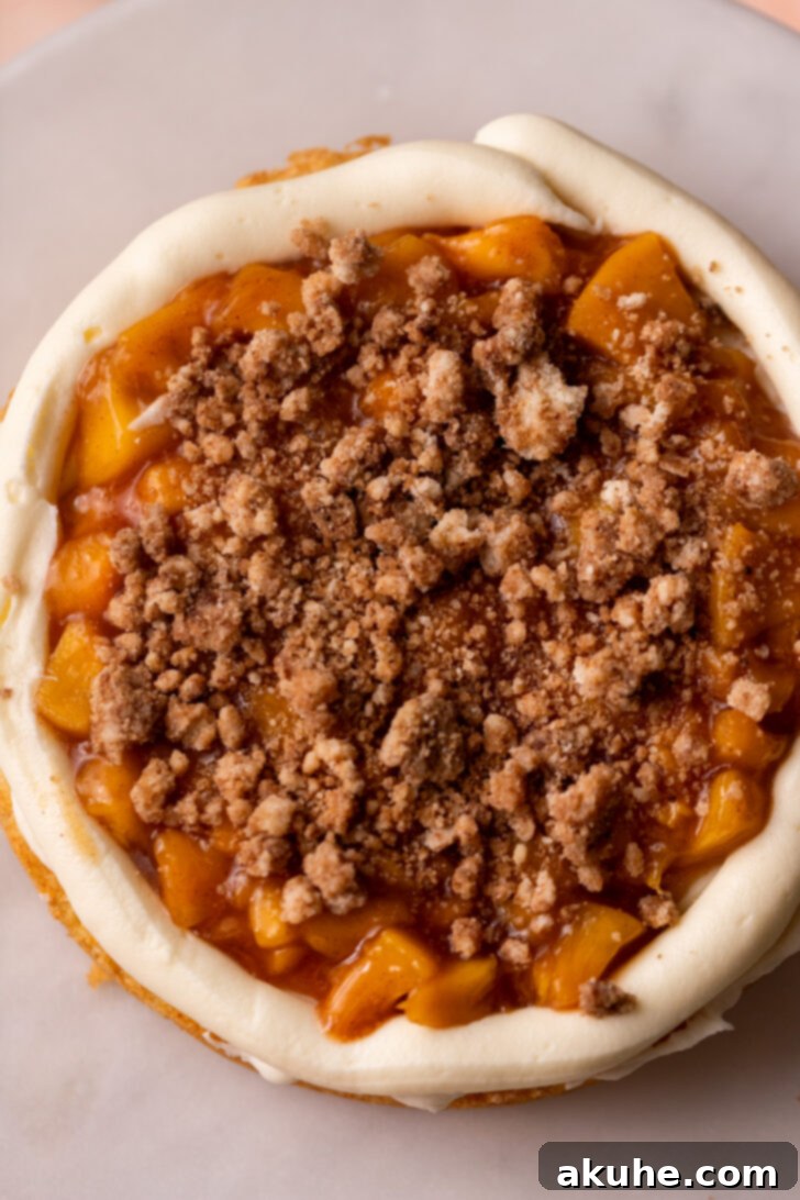 Peach filling and cinnamon crumble on top of a frosted cake layer.