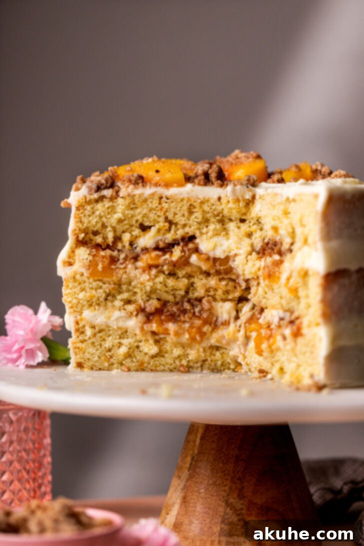 Close-up side view of the elegant Peach Cobbler Cake on a cake stand, highlighting its perfect layers.