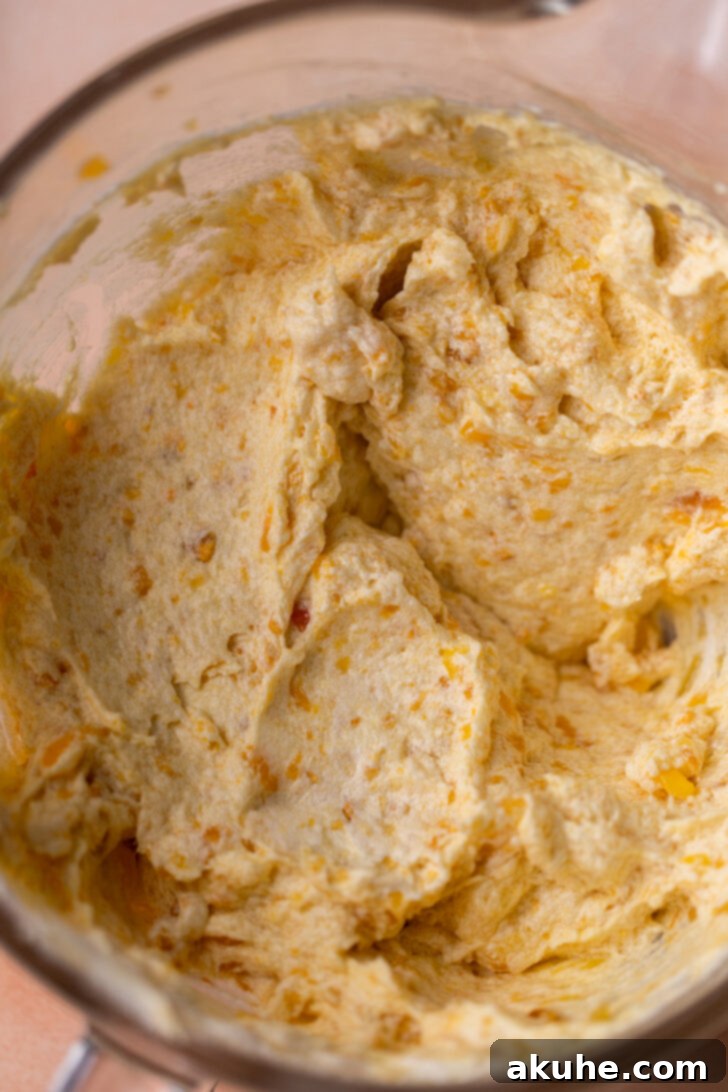 Wet ingredients being mixed in a bowl, with visible peach puree chunks.