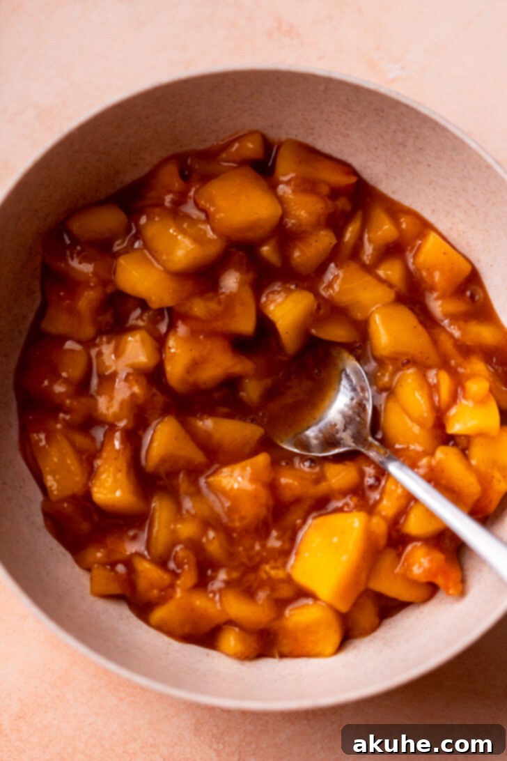Homemade peach pie filling in a bowl, showcasing its rich texture and color.
