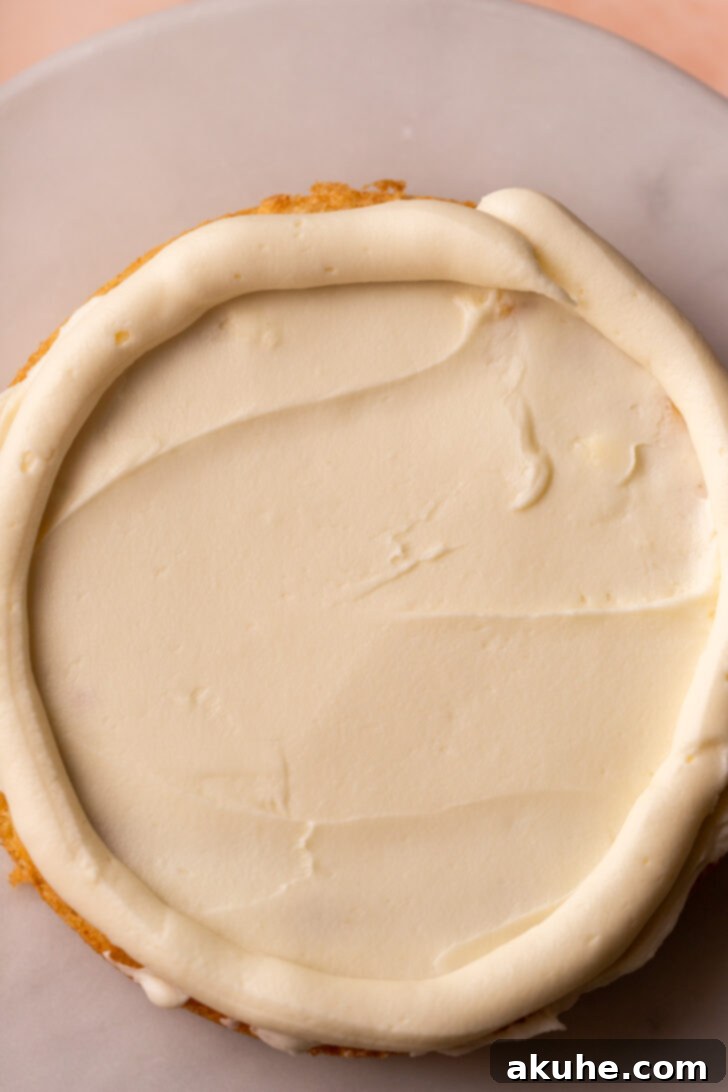 First cake layer frosted and a border piped around the edge.