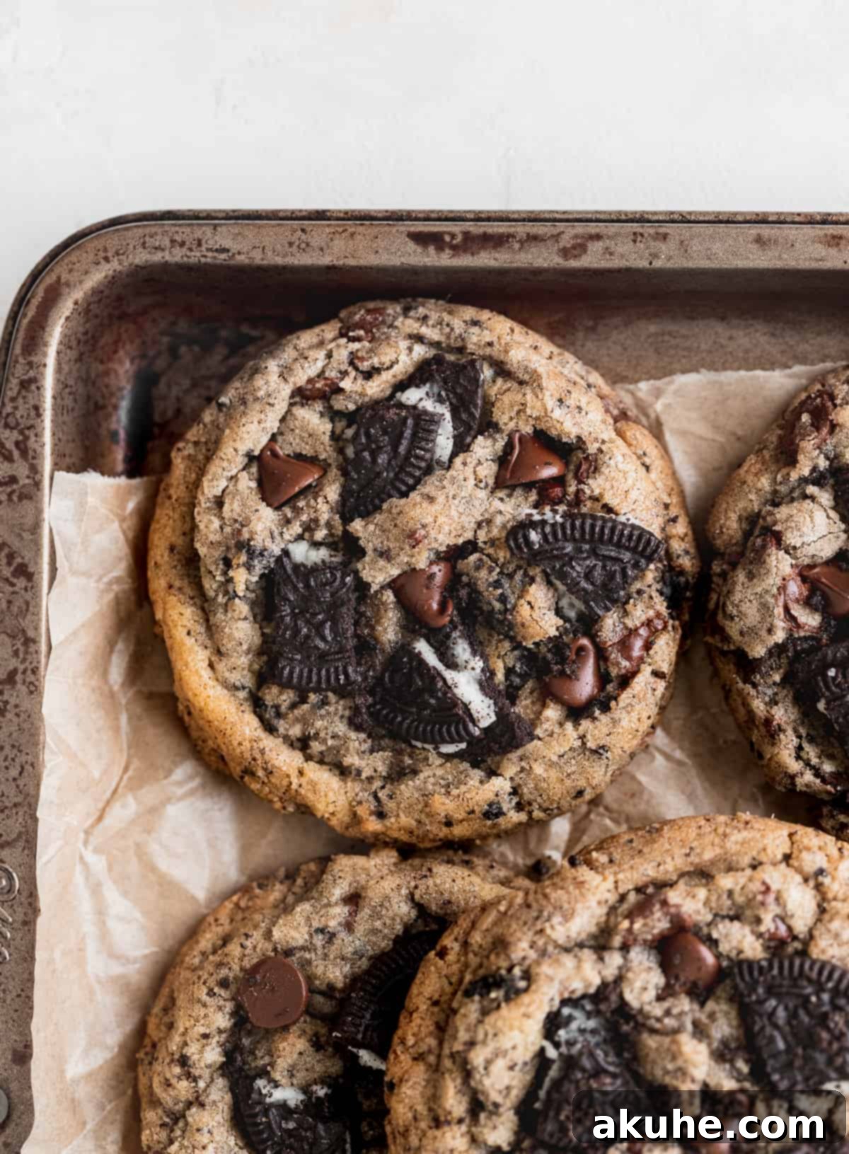 Decadent Oreo Chocolate Chip Cookies 8 A tray of freshly baked Oreo chocolate chip cookies cooling on a baking sheet, topped with extra Oreos and chocolate chips.