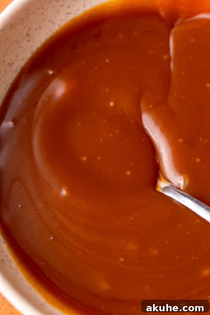 Velvet Caramel Indulgence 4 Golden-brown homemade caramel cooling in a clear glass bowl, showcasing its thick, rich texture.