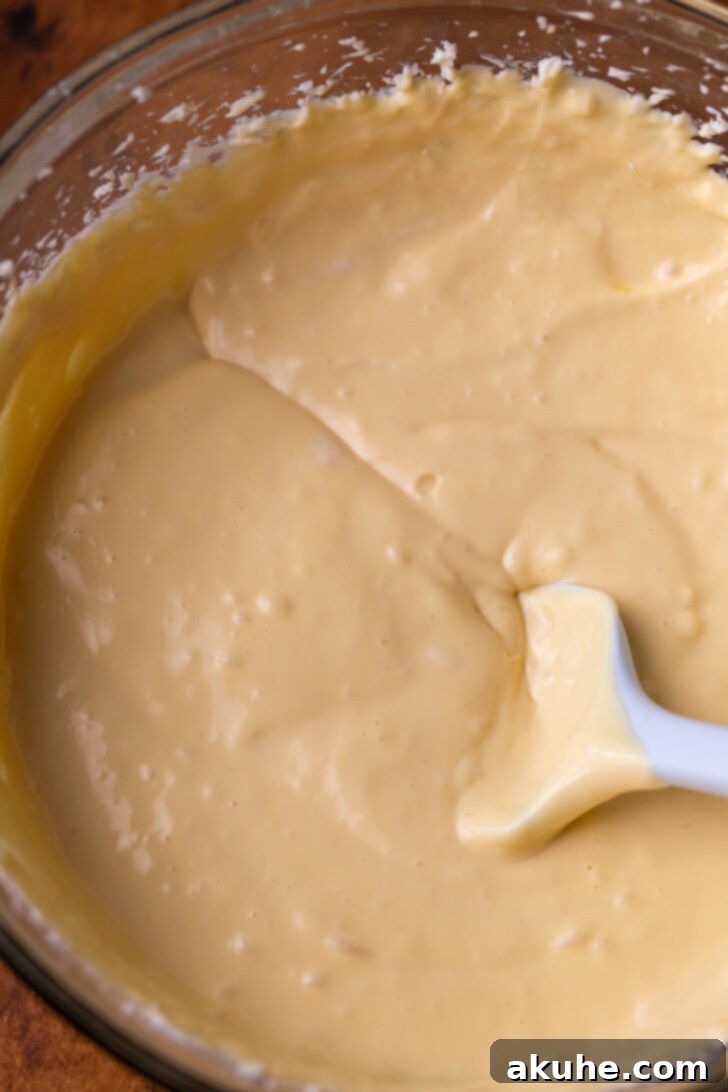 Velvet Caramel Indulgence 5 Smooth, golden-hued cheesecake batter in a mixing bowl, ready to be poured into the crust.