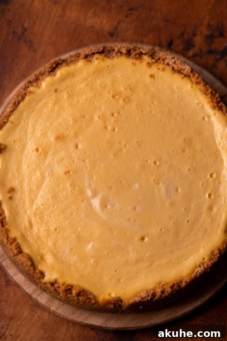 Velvet Caramel Indulgence 8 A perfectly baked and cooled caramel cheesecake resting on a wooden board, showcasing its smooth, golden surface before topping.