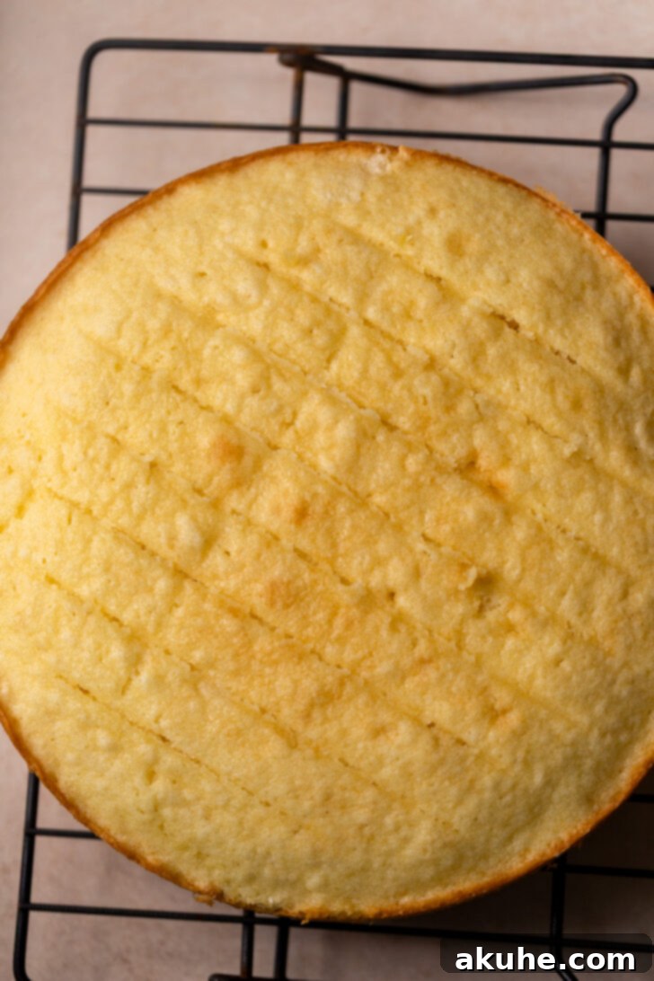 Classic Yellow Cake 6 Three golden-baked cake layers cooling on a wire rack, with one layer having its domed top neatly sliced off using a serrated knife.