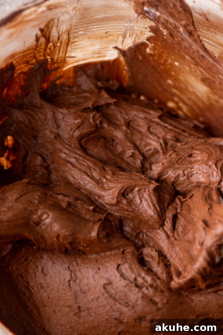 Classic Yellow Cake 7 A large bowl filled with rich, brown chocolate cream cheese frosting, showcasing its smooth and creamy texture.