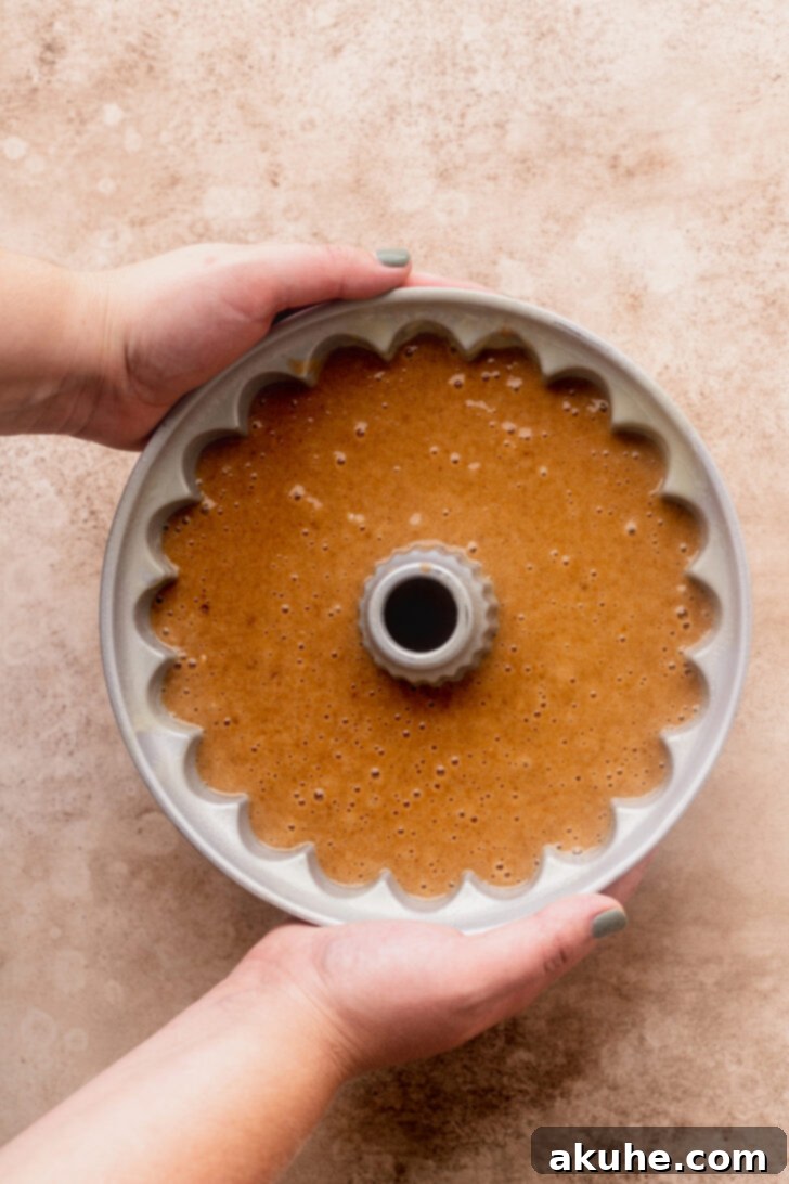 Spiced Apple Cider Donut Cake 6 Apple cider donut cake batter poured into a prepared bundt pan, ready for baking.