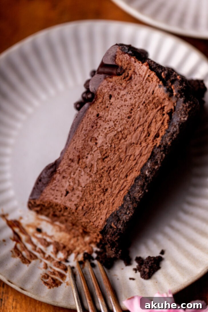 Top view of a generously sized slice of no-bake chocolate cheesecake, revealing its distinct layers of dark Oreo crust, creamy chocolate filling, and glossy ganache topping.