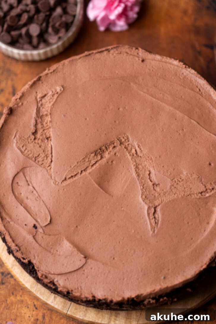A chilled no-bake chocolate cheesecake resting on a wooden board, ready for its ganache topping.