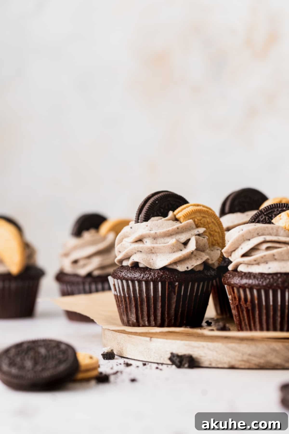 Decadent Oreo Cupcakes 2 Beautifully decorated Oreo cupcakes displayed on a rustic wooden board, showcasing their rich frosting and cookie garnishes.