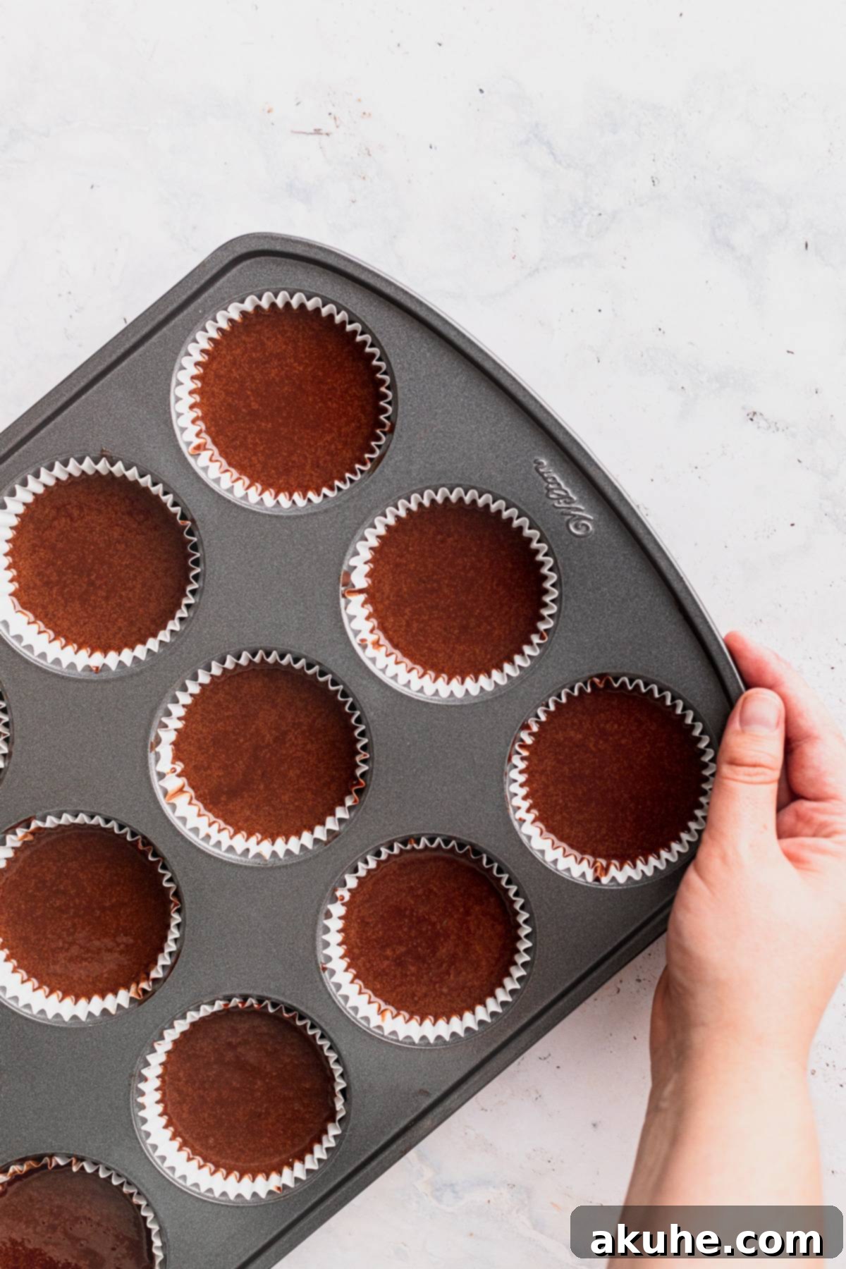 Decadent Oreo Cupcakes 6 Cupcake batter carefully scooped into paper liners within a muffin tin, ready for the oven.