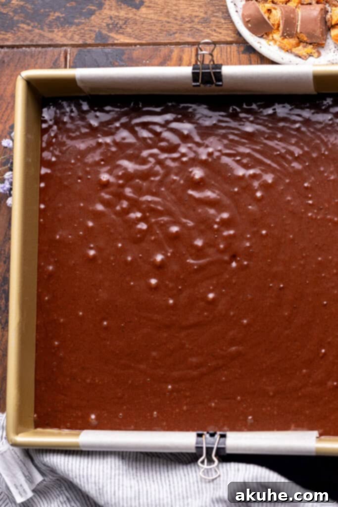 Decadent Butterfinger Crunch Cake 5 Chocolate cake batter evenly poured into a prepared square baking pan.