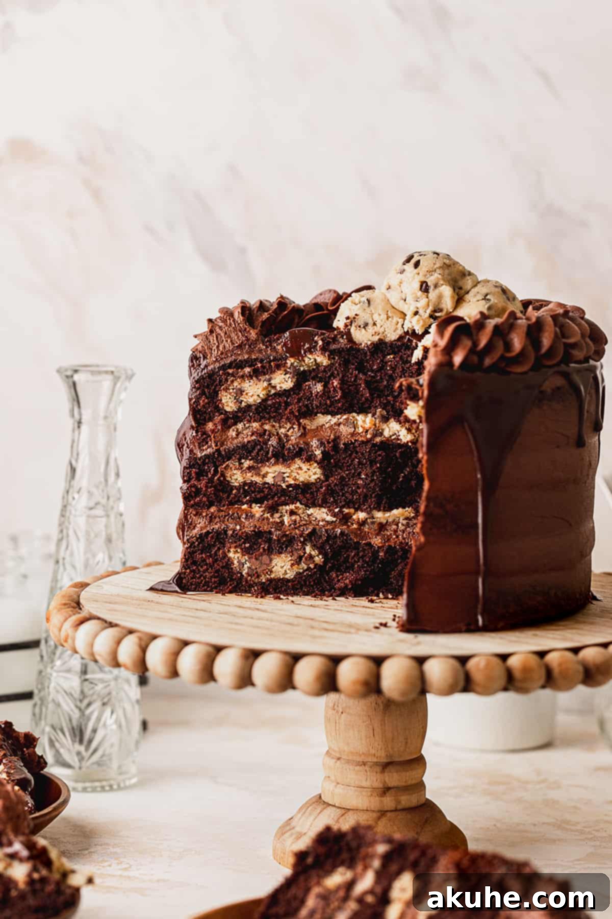 Decadent Cookie Brownie Cake 14 A large, layered chocolate cookie brownie cake, partially cut, on an elegant cake stand.