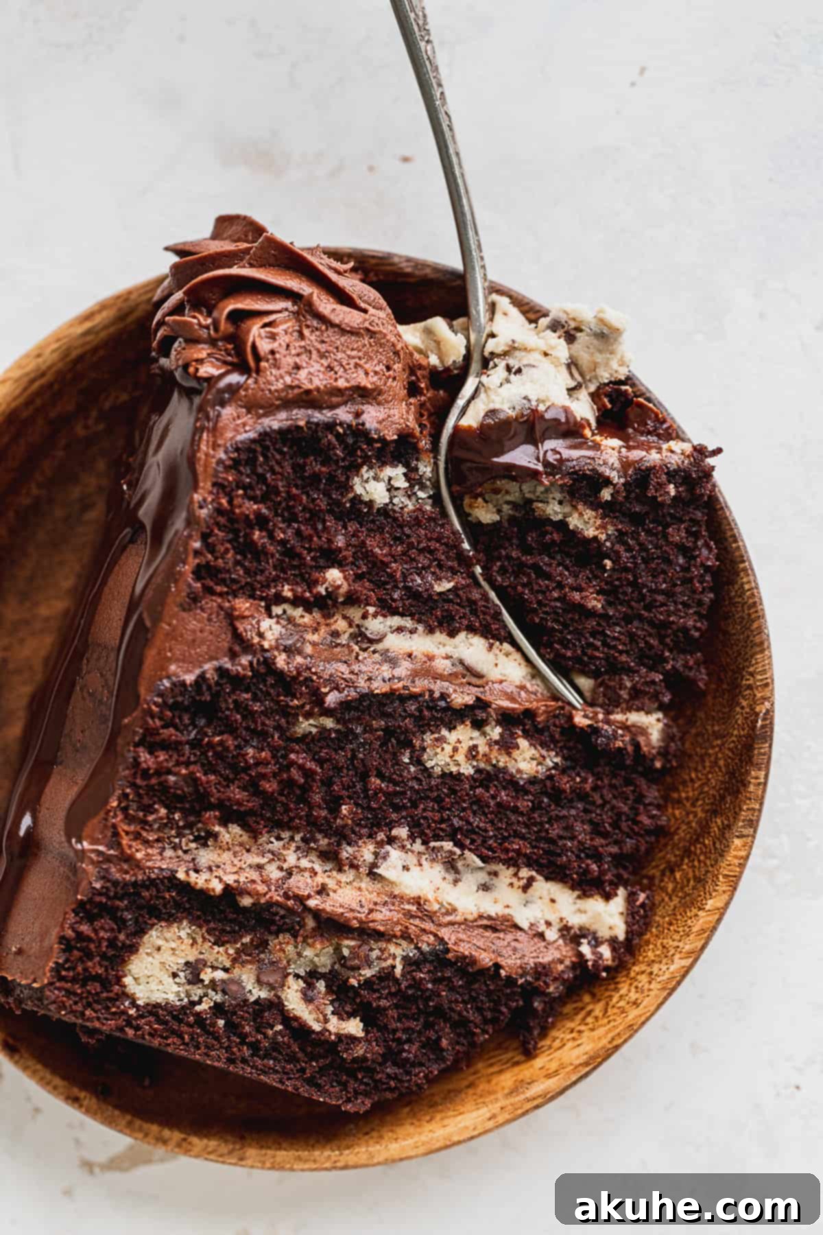 Decadent Cookie Brownie Cake 4 A slice of chocolate cookie brownie cake presented on a white plate with a fork.