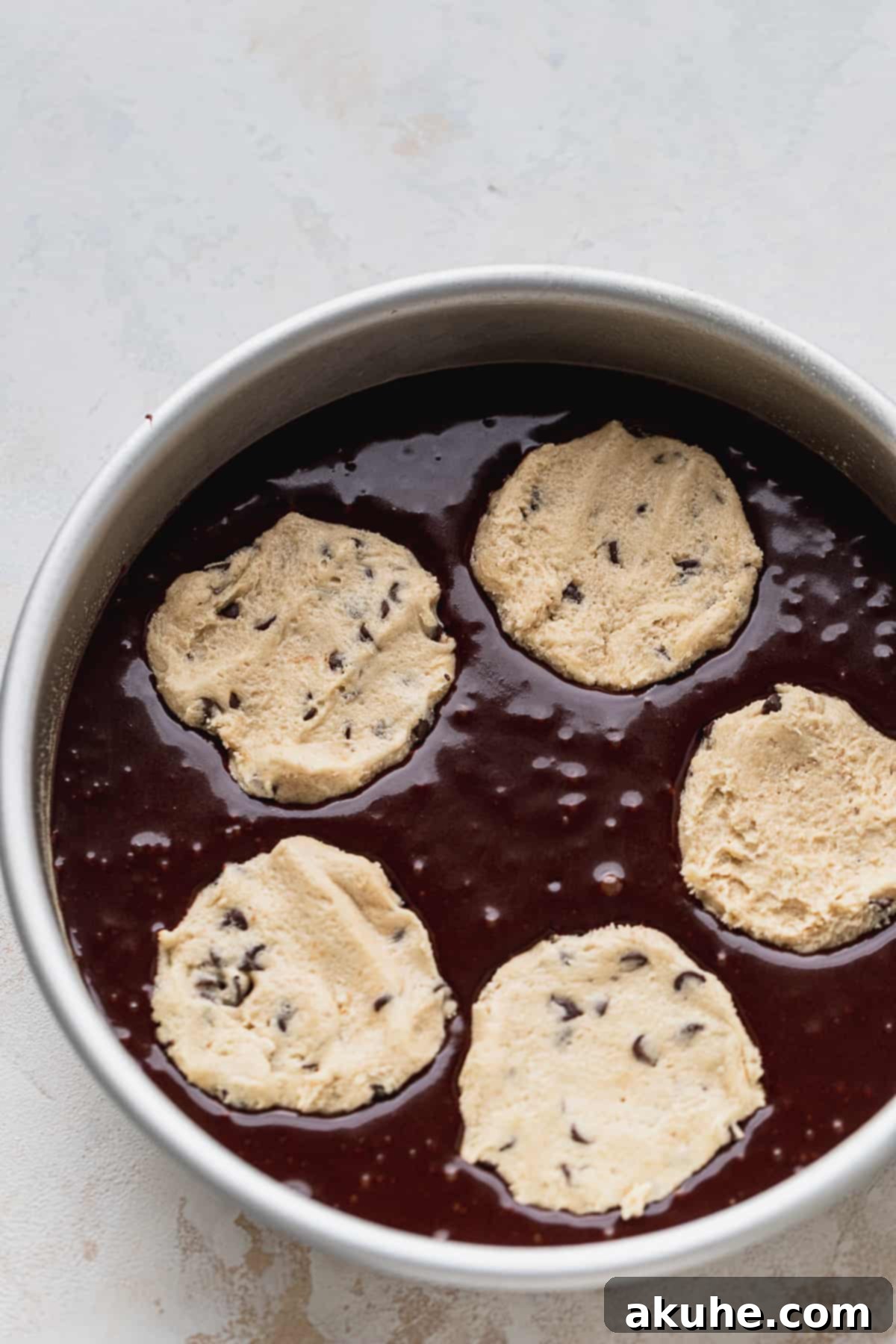Decadent Cookie Brownie Cake 9 Cookie dough discs placed on top of unbaked cake batter in a round pan.