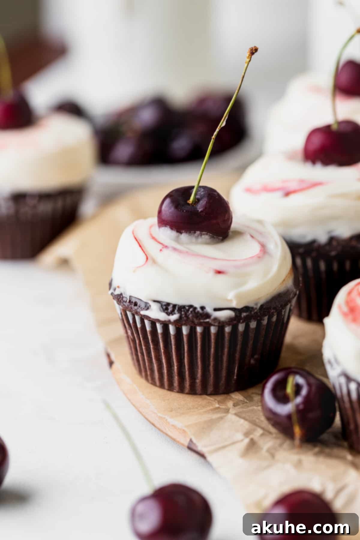 Decadent Black Forest Cupcakes 2 A perfectly crafted Black Forest cupcake resting on a rustic wooden board, showcasing its rich chocolate base, vibrant cherry filling, and elegant cream cheese frosting.