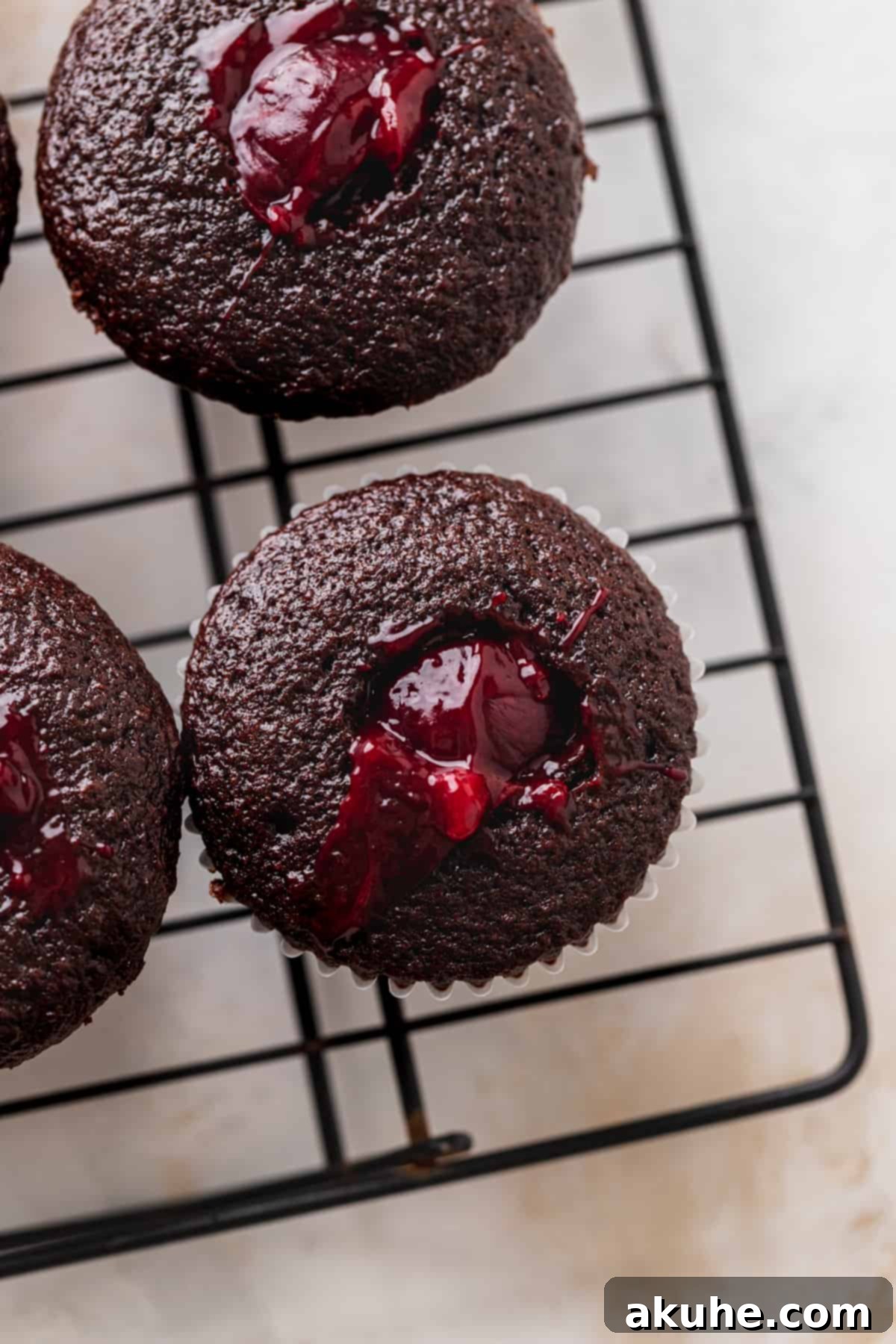 Decadent Black Forest Cupcakes 7 Baked chocolate cupcakes, each cored and filled with a generous dollop of cherry pie filling, ready for the next step of decoration.
