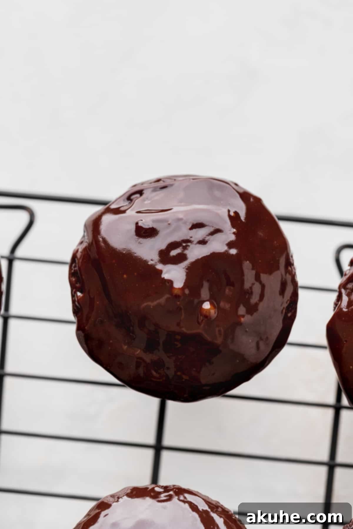 Decadent Black Forest Cupcakes 8 A freshly chocolate-dipped cupcake resting on a wire rack, allowing the excess ganache to drip and set.