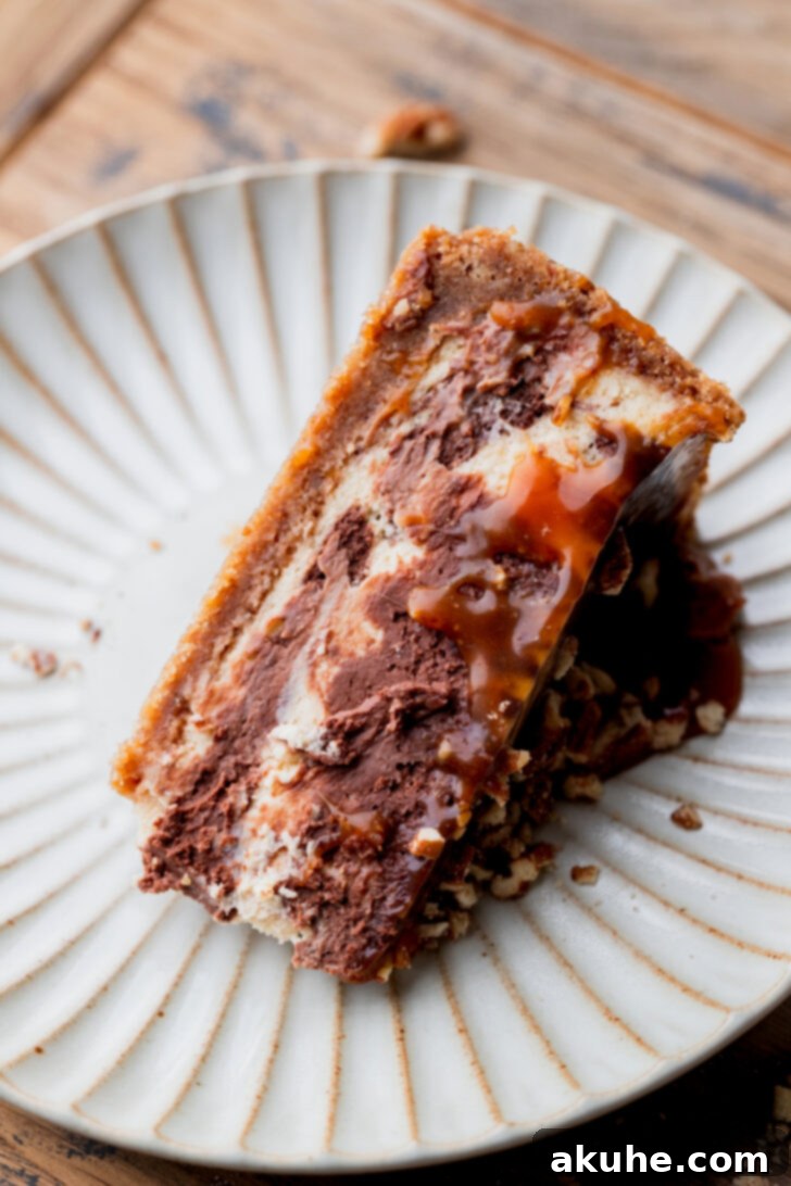 A beautifully presented single slice of Turtle Cheesecake on a white plate, highlighting the layers and toppings.