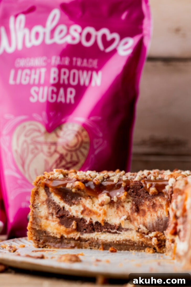 A close-up side view of the Turtle Cheesecake, showcasing its distinct layers: the thick pecan crust, swirled cheesecake, and generous caramel and pecan topping.