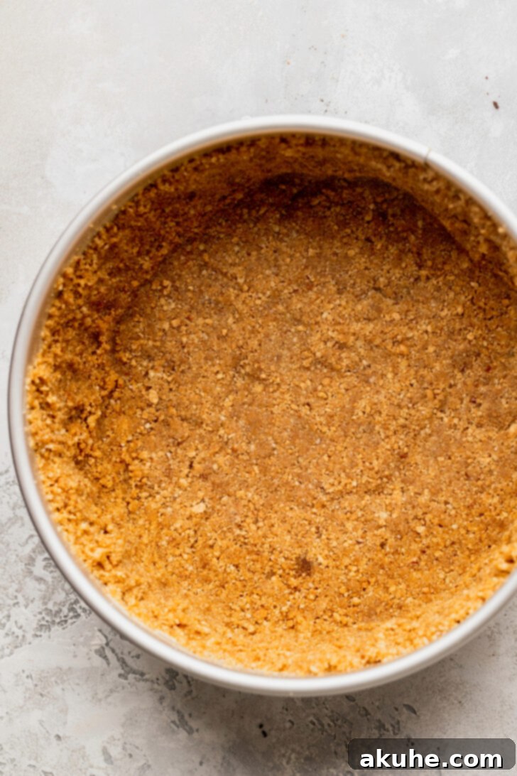Graham cracker and pecan crust pressed firmly into a springform pan, ready for the cheesecake batter.