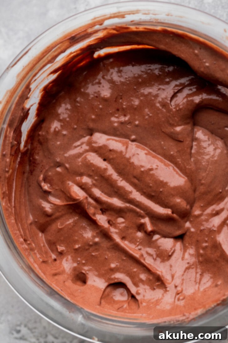 The separate bowl of cheesecake batter with cocoa powder and extra sugar, ready to be mixed into a dark, rich chocolate batter.