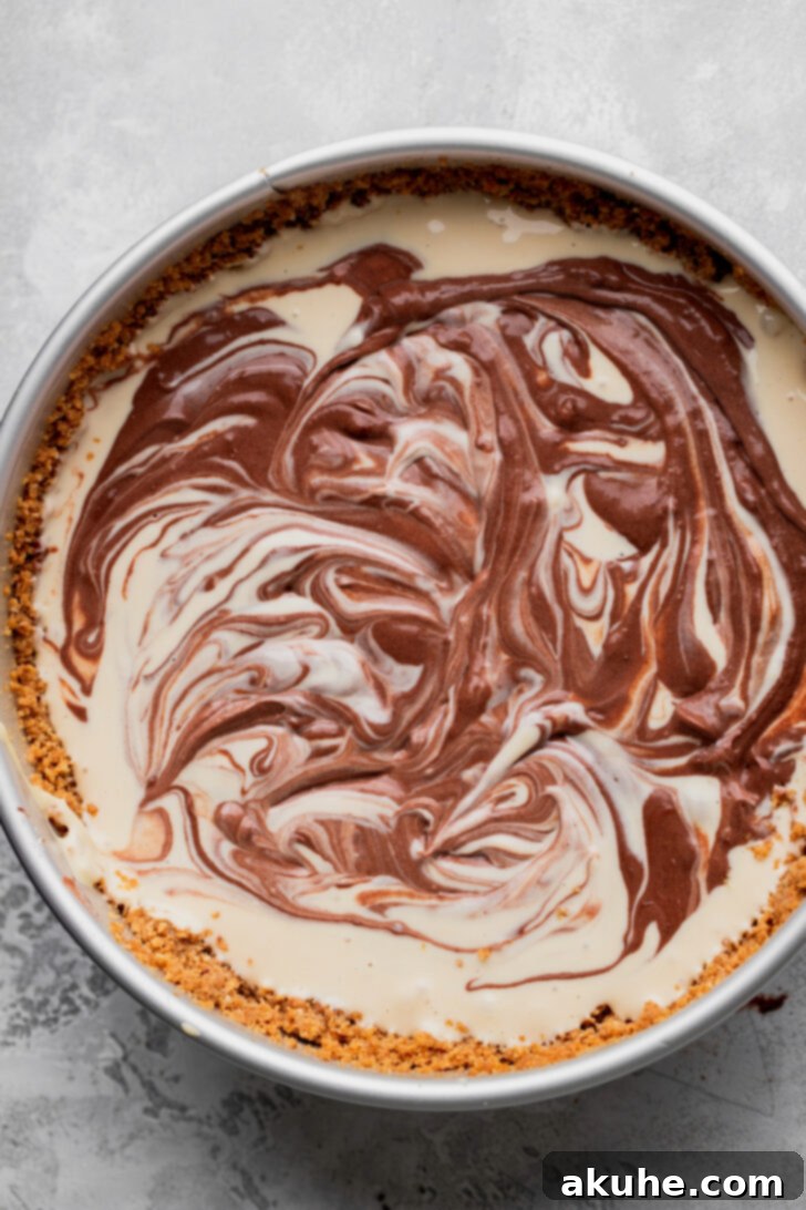 The cheesecake pan filled with beautifully swirled brown sugar and chocolate batters, showcasing intricate patterns.