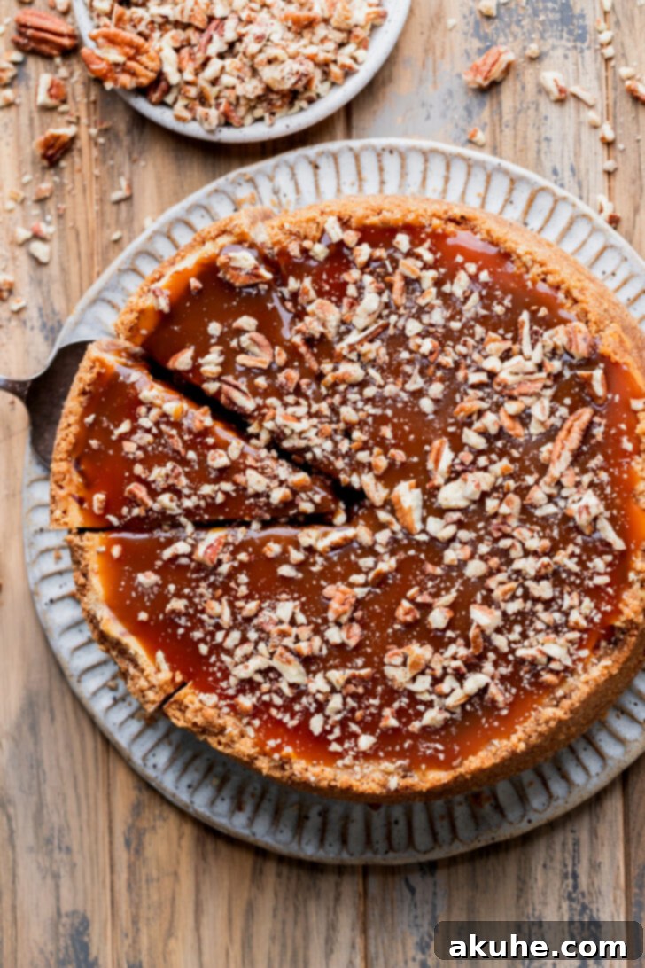 An overhead view of the finished Turtle Cheesecake, elegantly topped with swirls of salted caramel and a generous scattering of pecans.