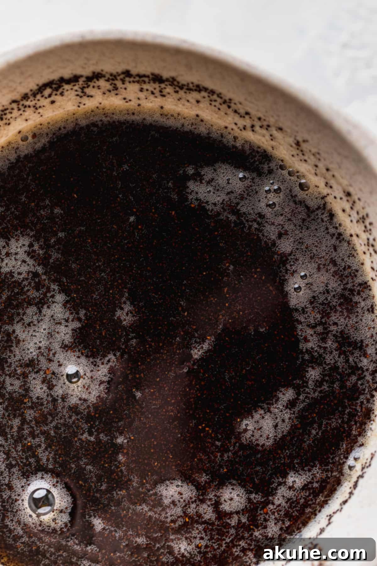Close-up of golden brown butter with espresso powder soaking in a glass bowl.