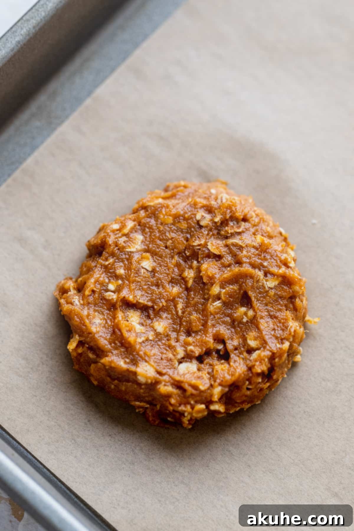 Scooped cookie dough placed on parchment paper on a baking sheet.