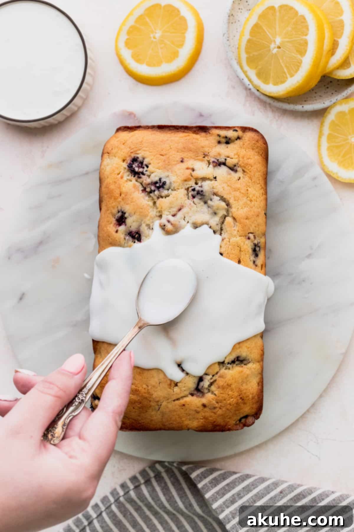 Zesty Blackberry Lemon Loaf 9 Spreading lemon glaze on top of bread.