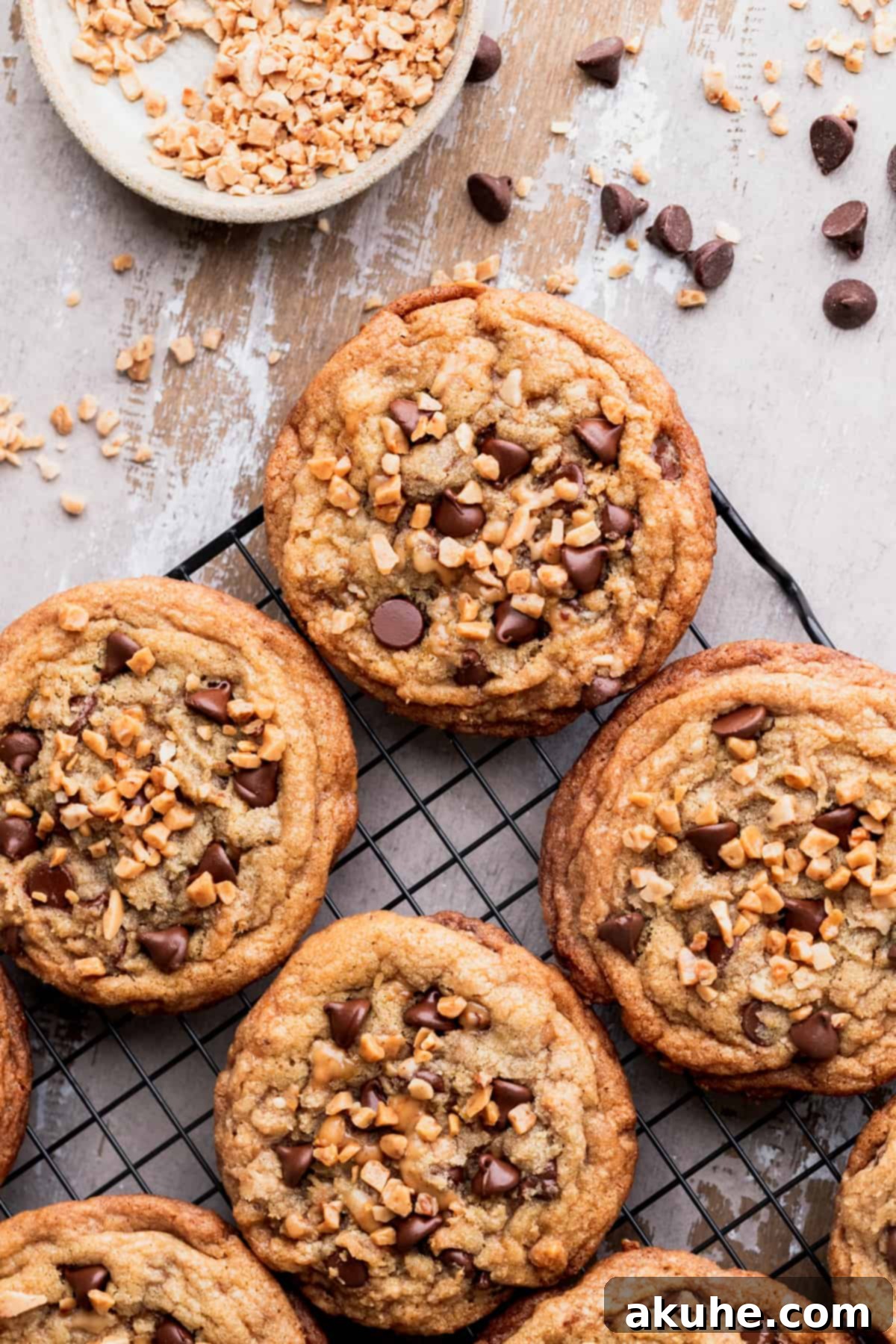 Several brown butter toffee cookies on a cooling rack, some with extra toffee pieces on top.