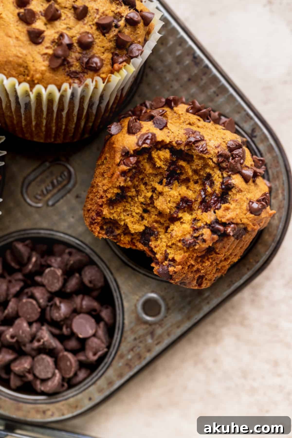 A perfectly baked pumpkin chocolate chip muffin with a bite taken out, revealing its moist interior and mini chocolate chips.
