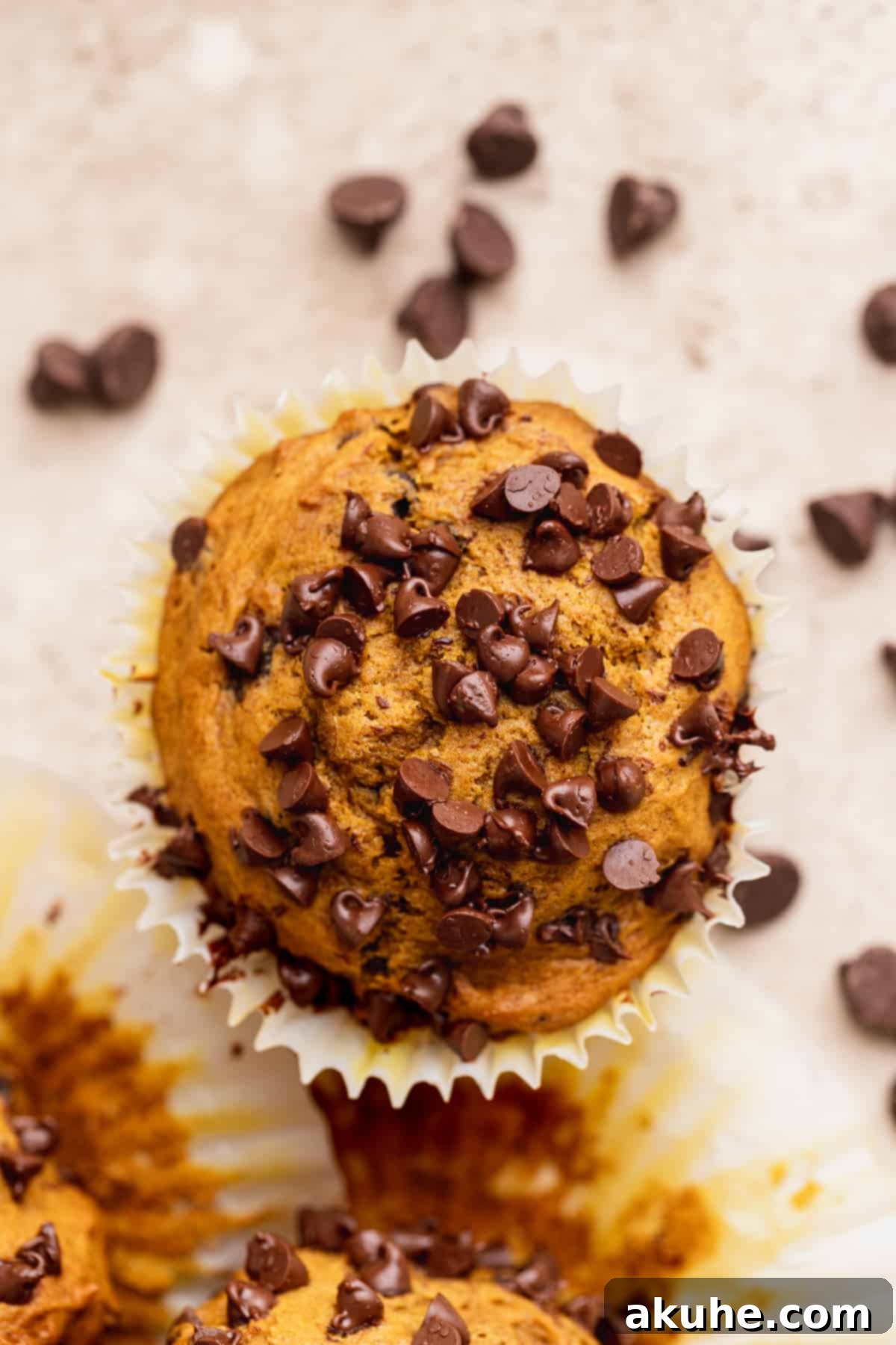 Close-up of the perfectly baked, domed top of a pumpkin chocolate chip muffin, showing its moist texture.
