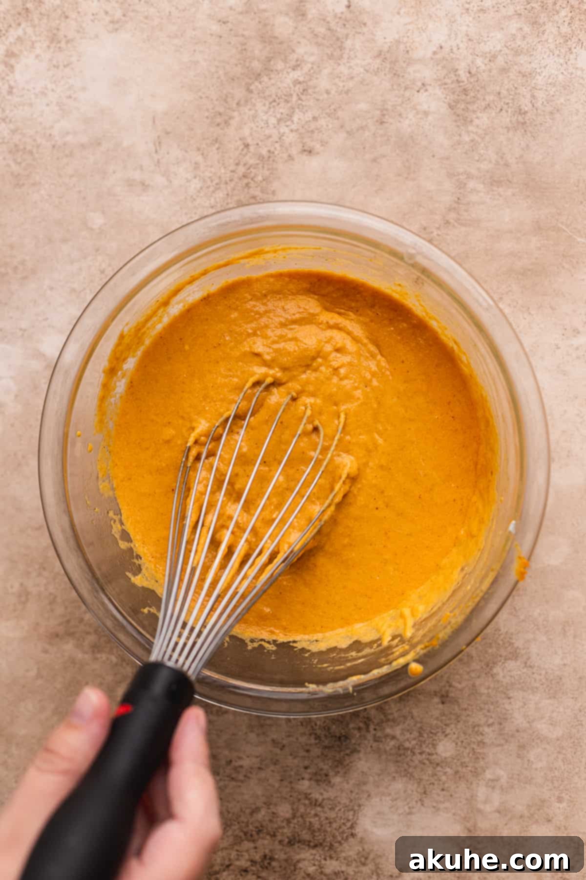Mixing wet ingredients in a glass bowl.