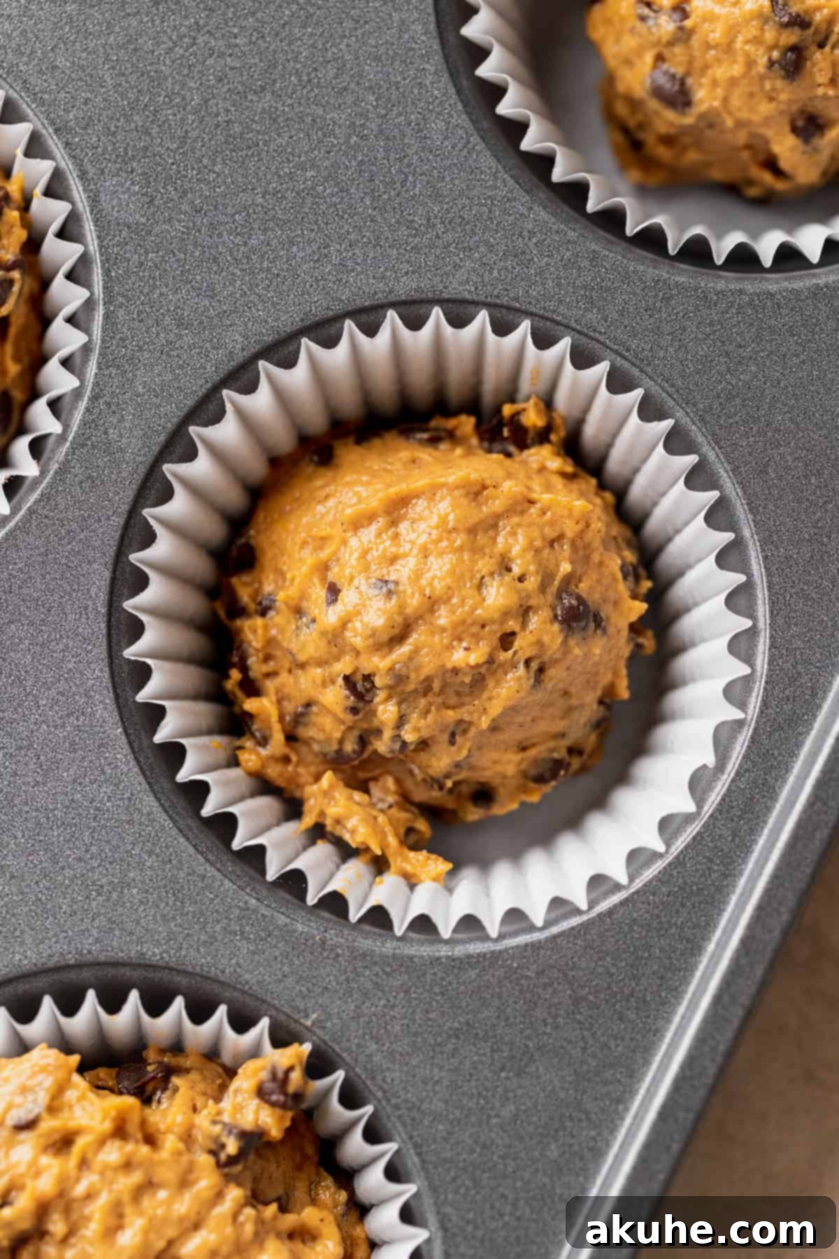 Muffin batter scooped into a muffin pan with liners.
