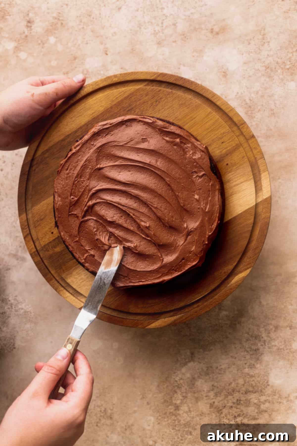 Expertly spreading rich chocolate frosting onto a cake layer, ready for the next step.