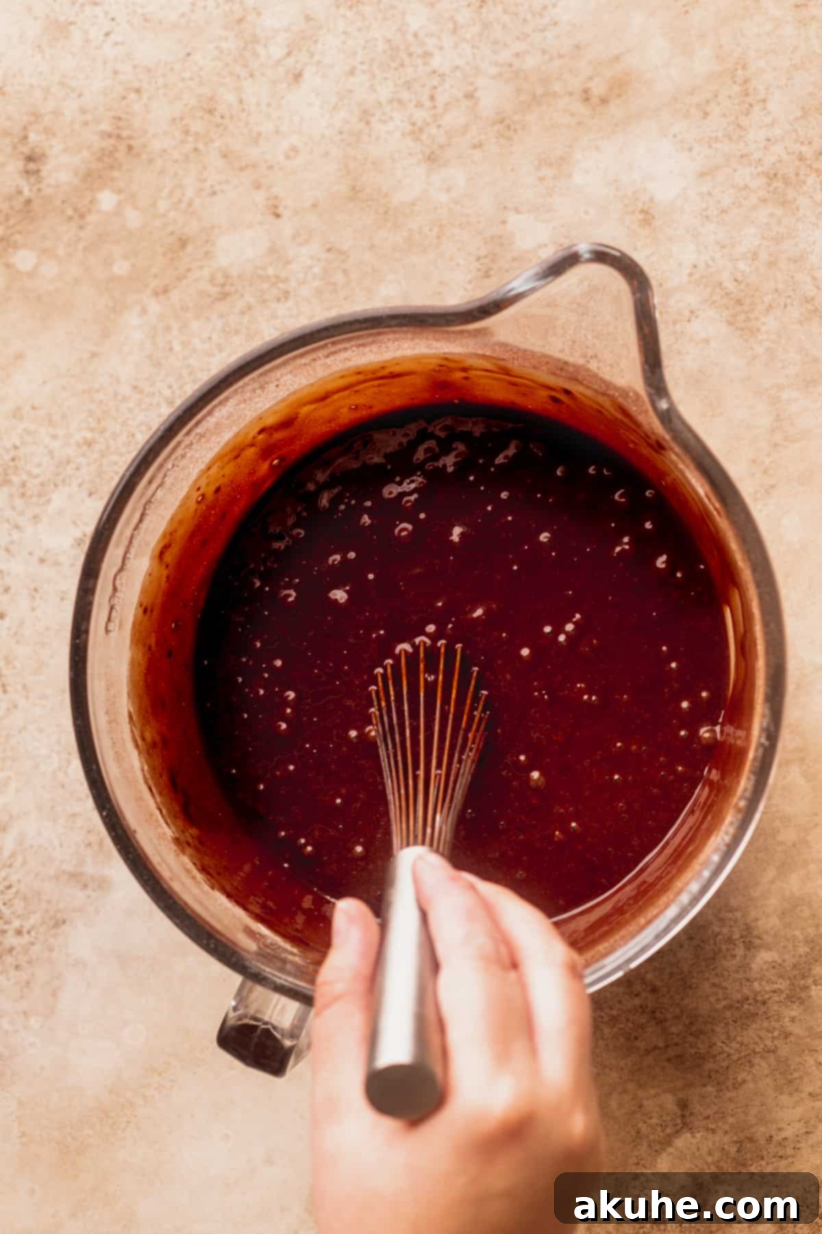The chocolate cake batter being gently stirred in a glass bowl, ensuring a perfect consistency.