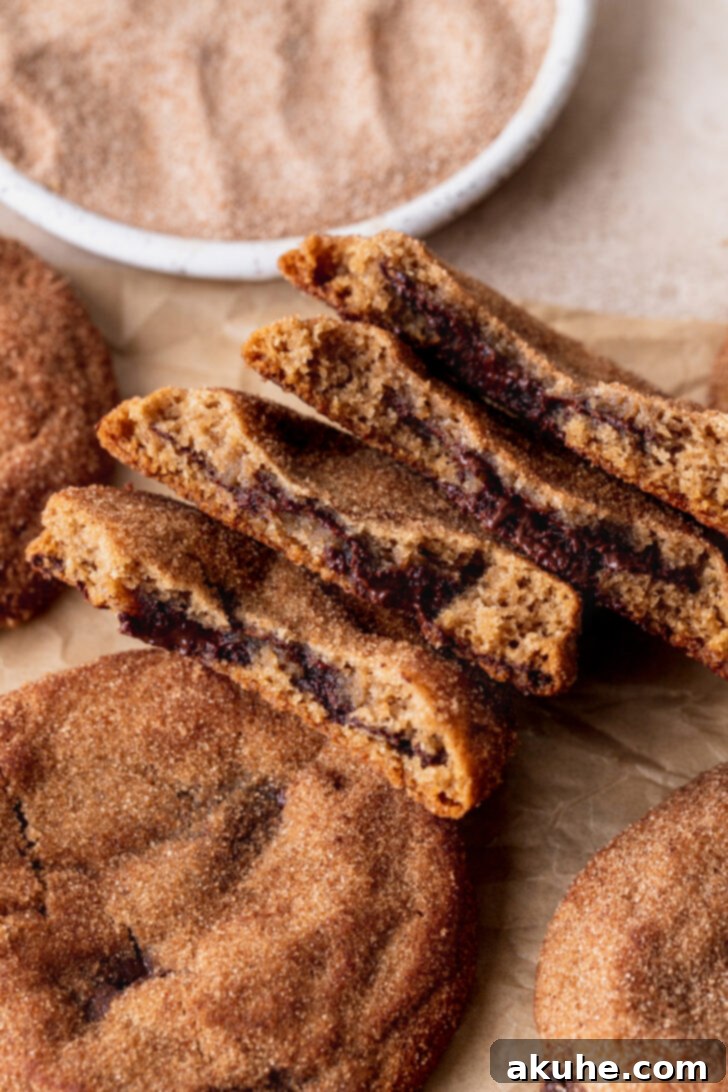 Churro Cookie Delights 3 A plate of freshly baked churro cookies, some whole and one split to show the gooey chocolate inside, dusted with cinnamon sugar.