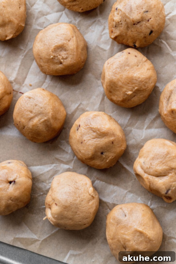 Churro Cookie Delights 7 Multiple cookie dough balls, some rolled and some waiting, on a baking sheet.