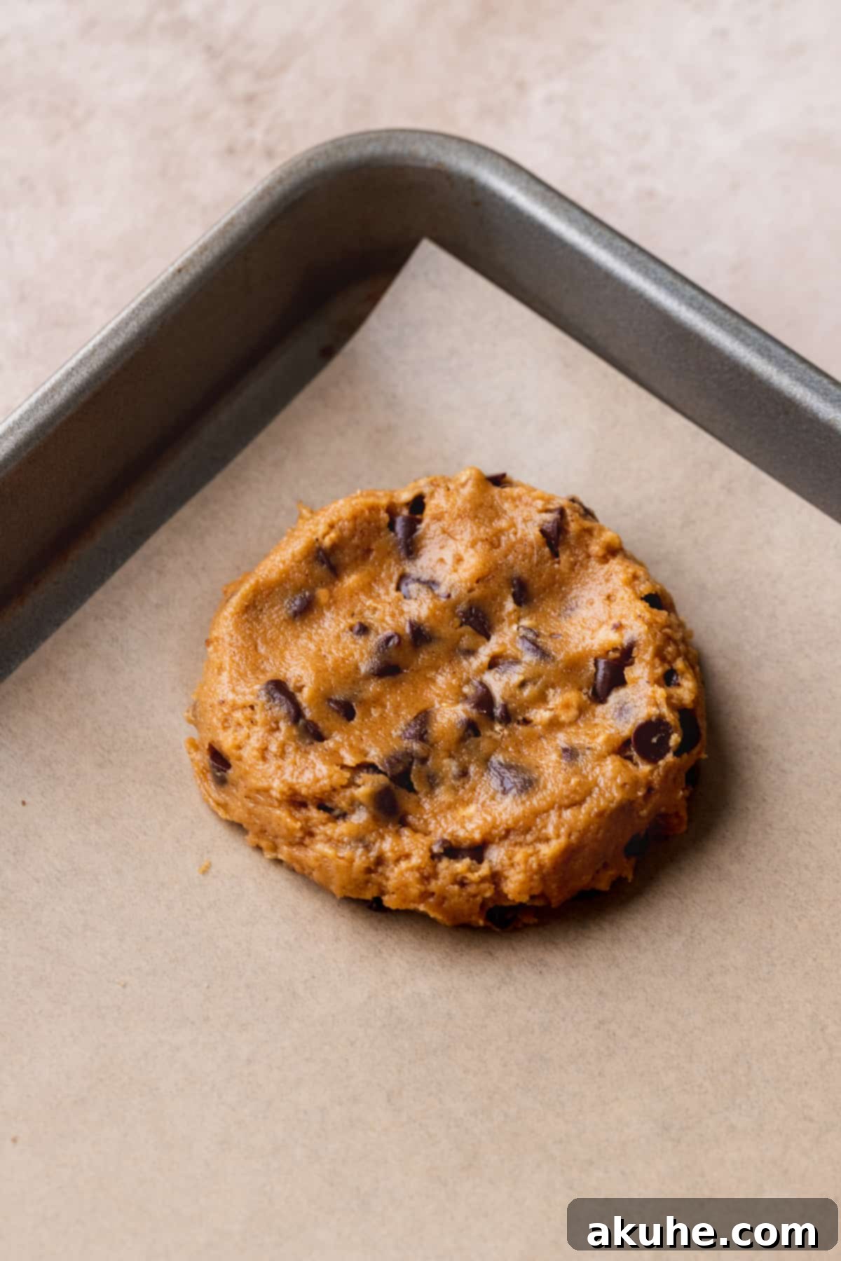 Pumpkin S'mores Cookies 7 A pressed down cookie dough ball on parchment paper, ready for baking.